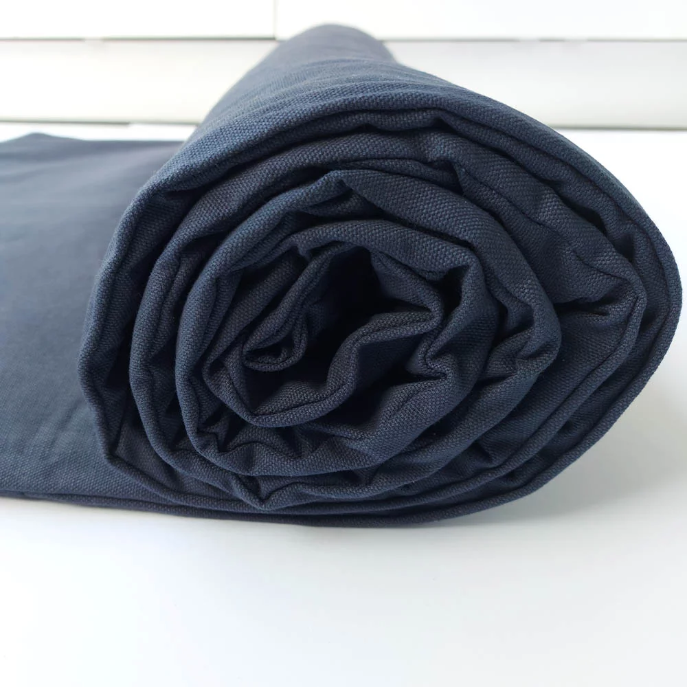 Bio Yogamatte aus Baumwolle in beruhigendem Grünton, auf Holzfußboden ausgebreitet, ideal für Yoga und Meditation.