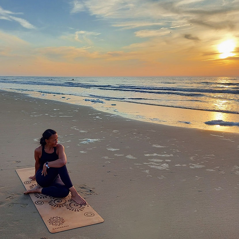 Frau am Strand Sonnenuntergang in Yogapose sitzend_Moon eclipse Yogamatte