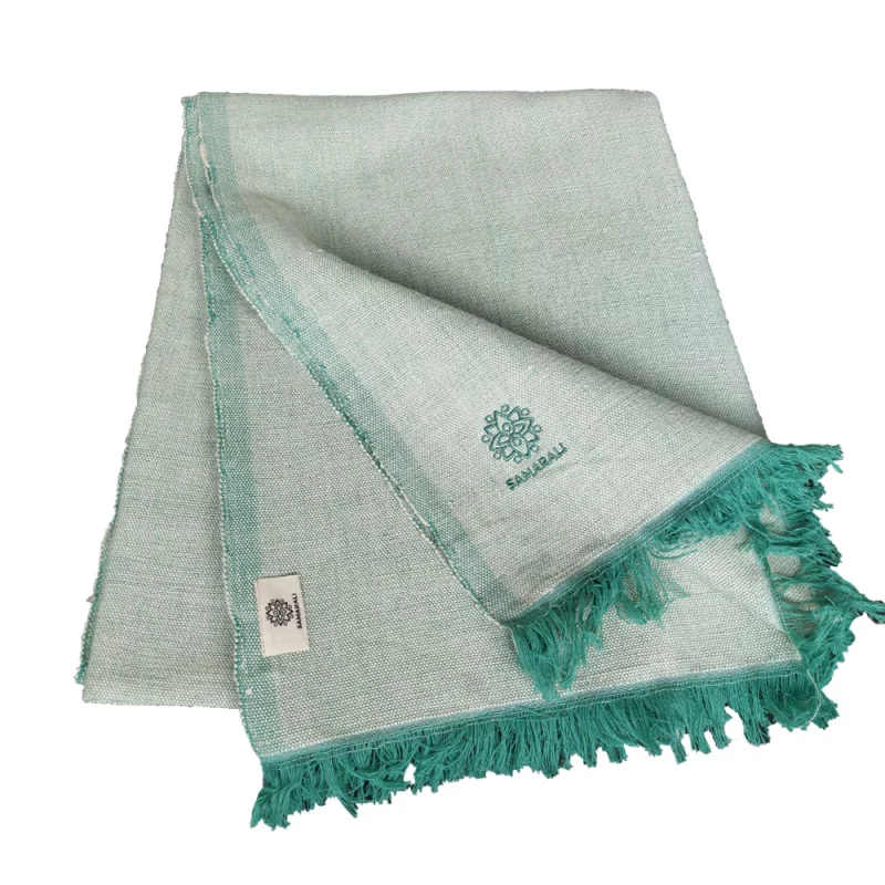 Yogadecke aus Bio Baumwolle in grün, handgefertigt und nachhaltig, liegt auf einer Holzoberfläche.
